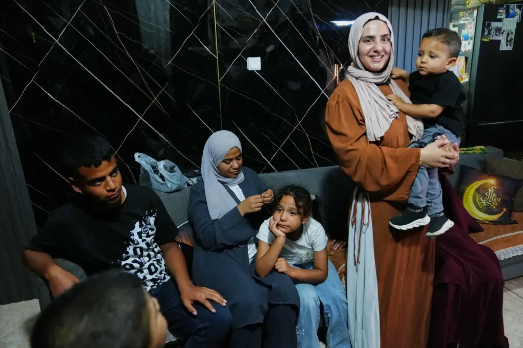 Mais Al-Gharam holds her son as she stands with her...