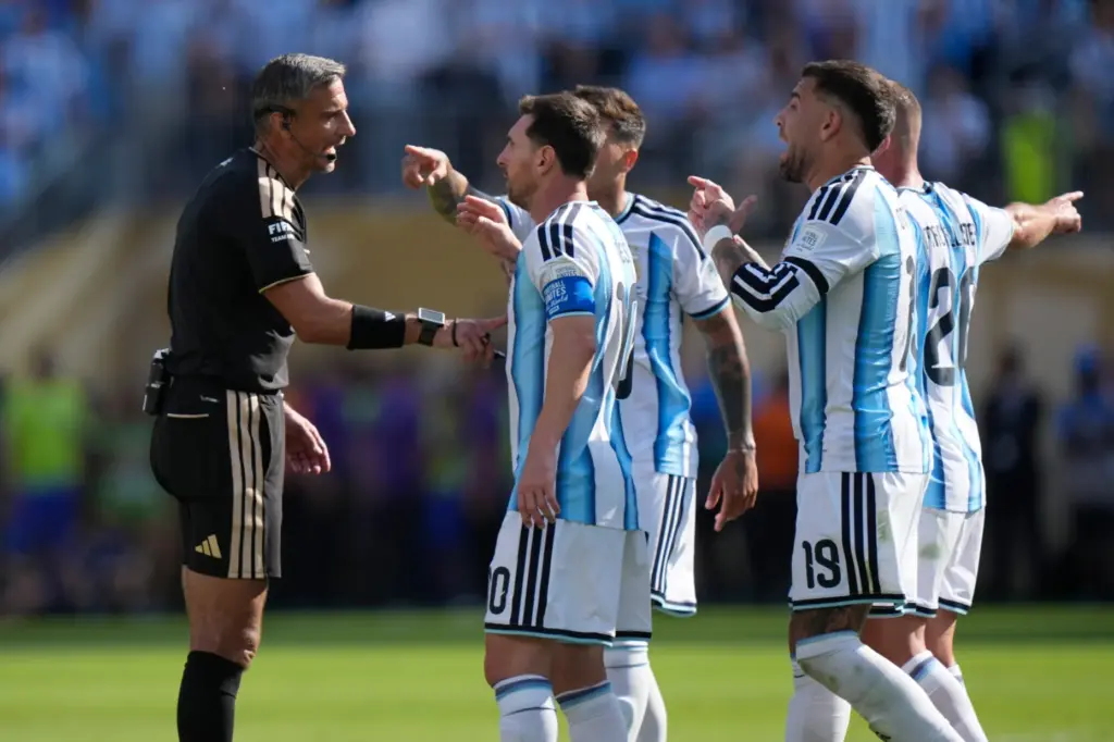 Argentina players argue with the referee Slavko Vincic, of Slovenia,...