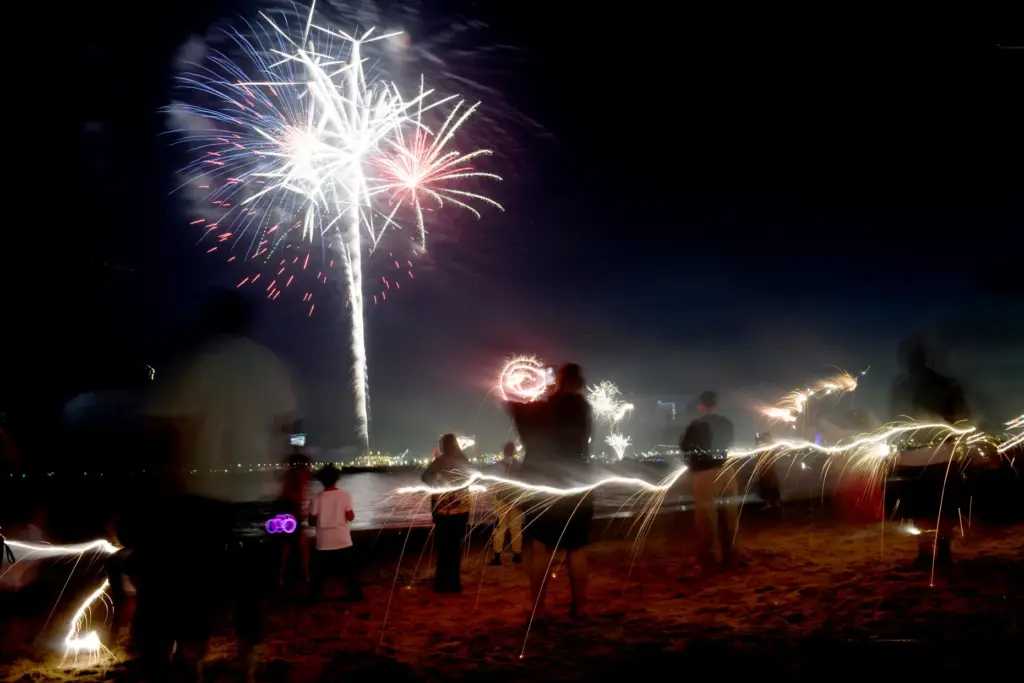 Children play with sparklers as simultaneous fireworks displays in Long...