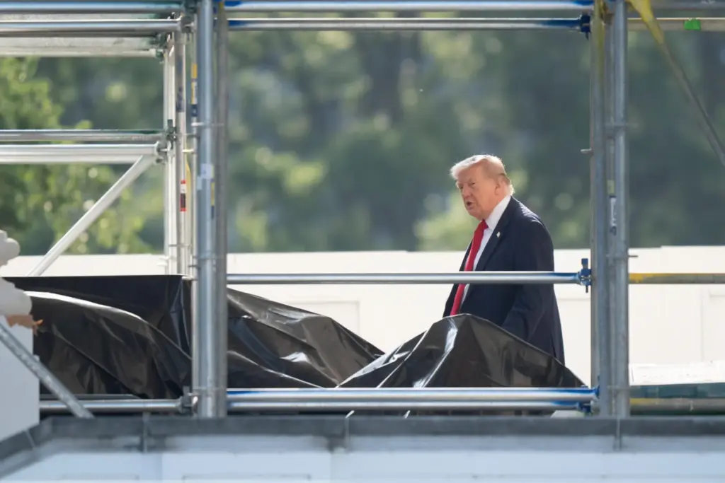 President Donald Trump walks through scaffolding as he leaves the White House.