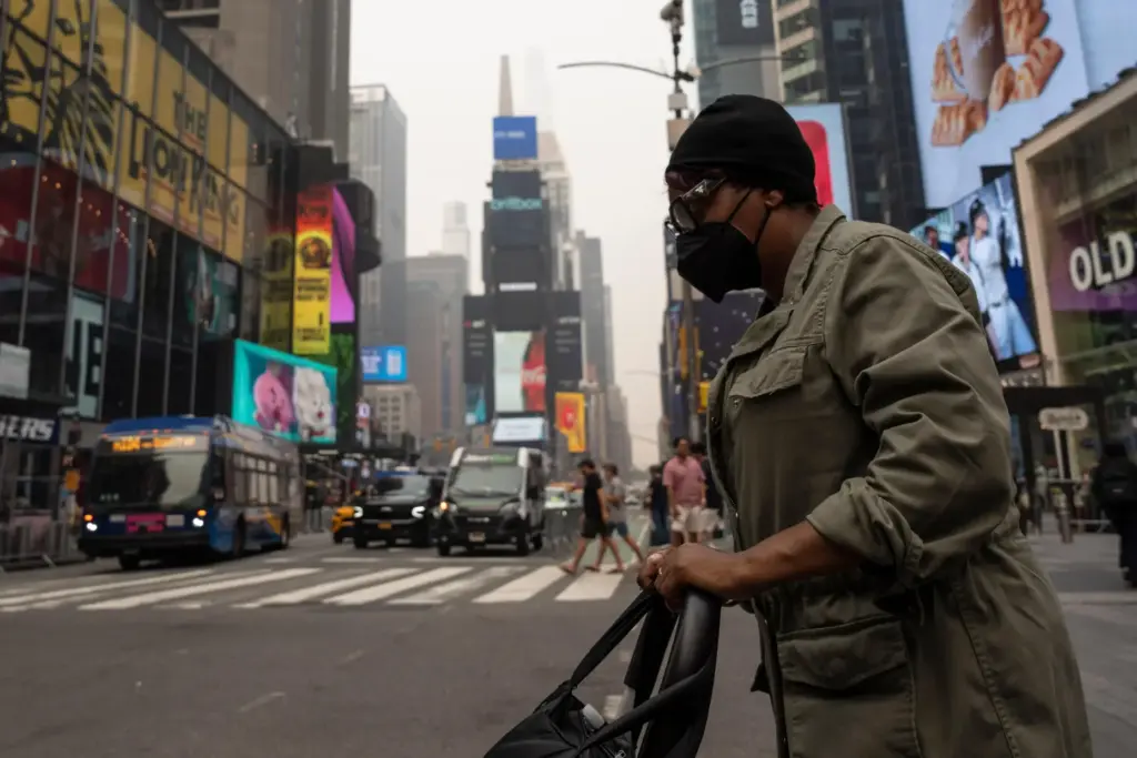 A person wearing a mask walks in Times Square as smoke from wildfires blankets the sky.