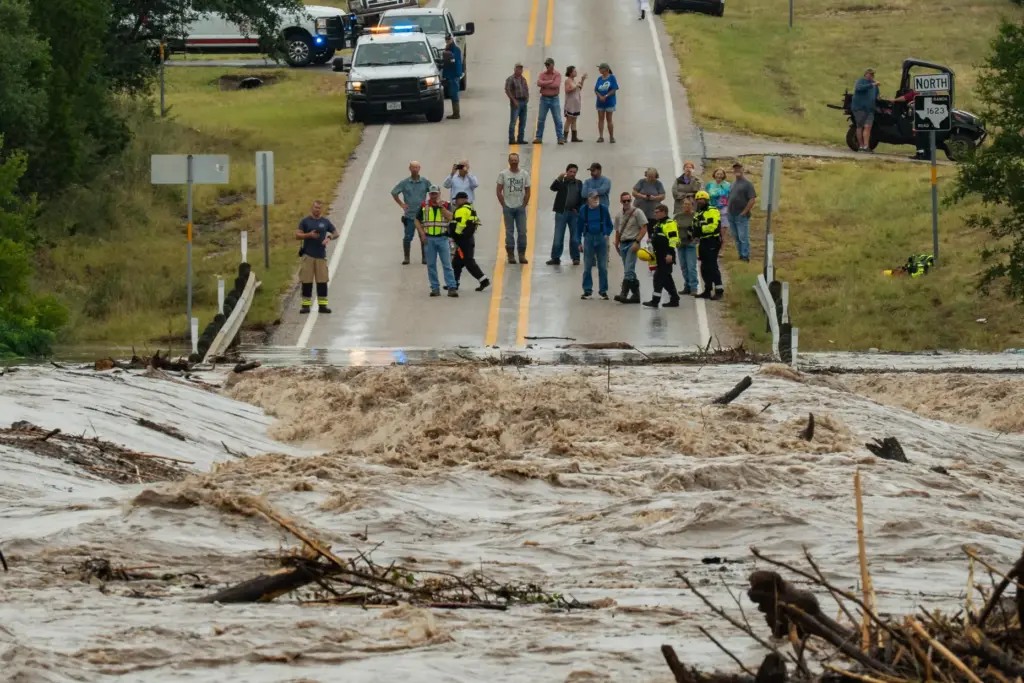 People gather to watch as the Perdenales River floods Ranch Road 1623.