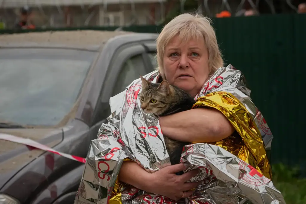 A woman carries her cat out of a damaged apartment building following a Russian missile attack.