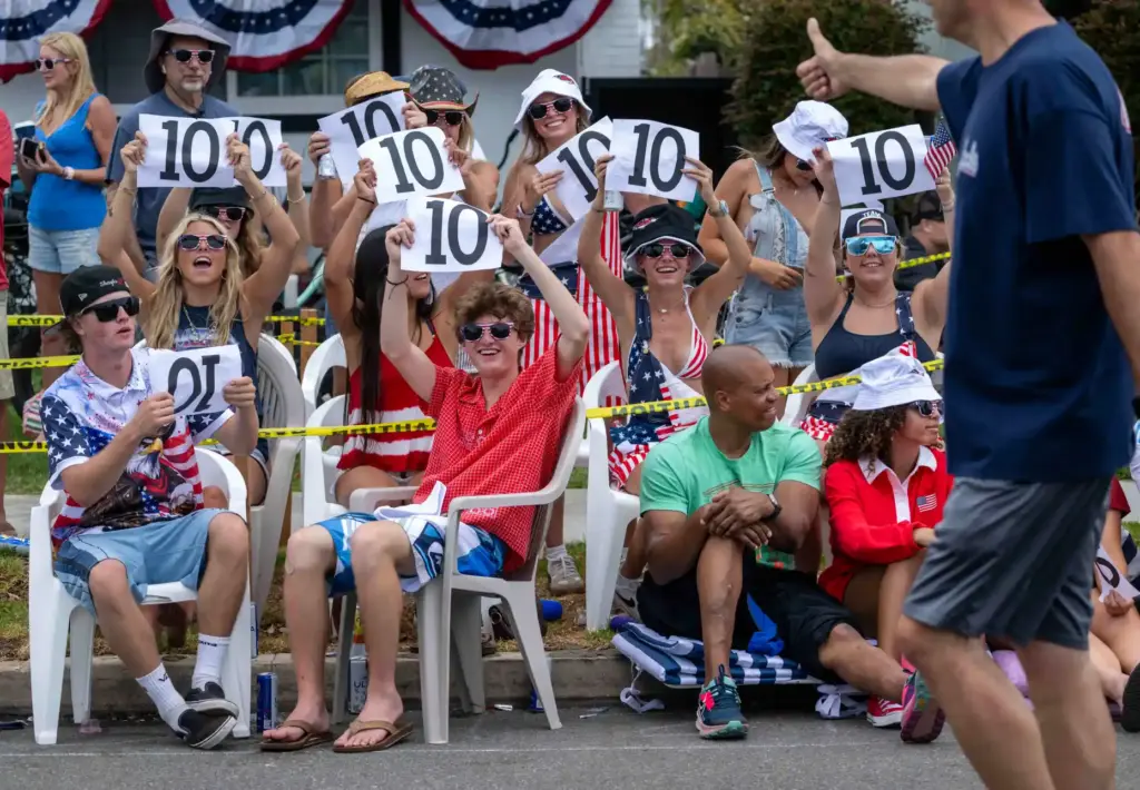 Local residents hold up scores for passing parade participants as...