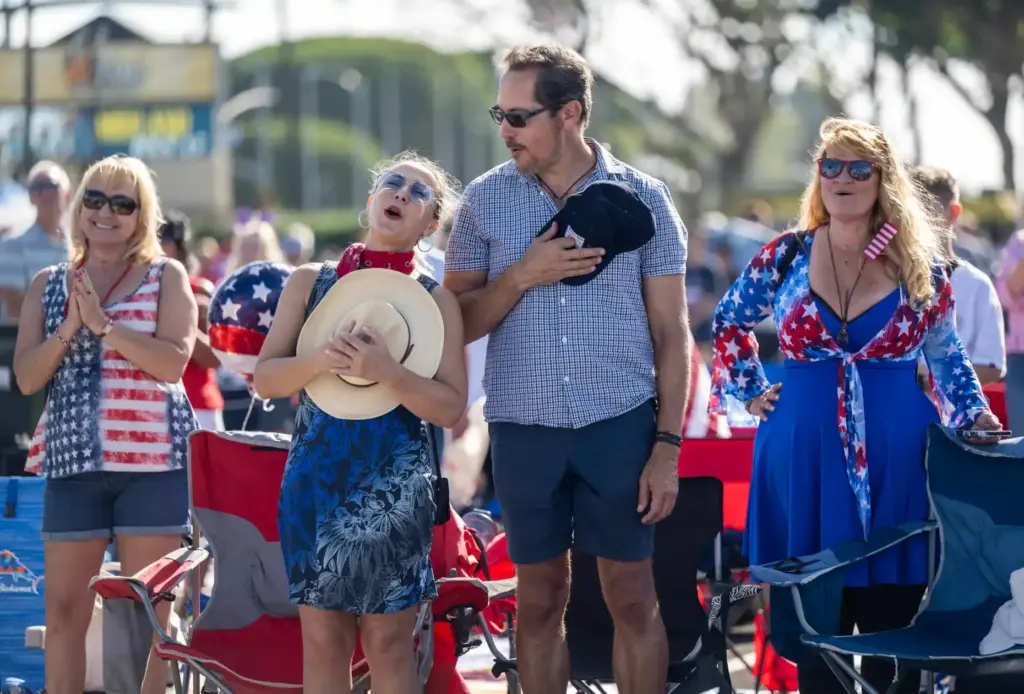 Audience members sing along to the national anthem during the...