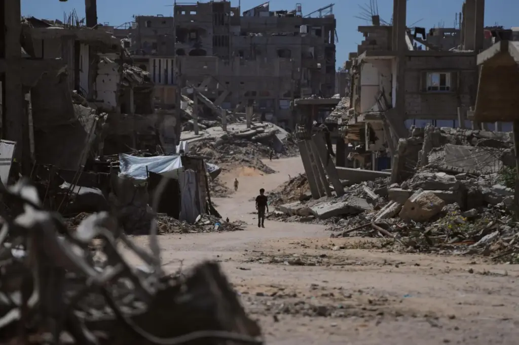 A Palestinian child walks along a street surrounded by buildings...