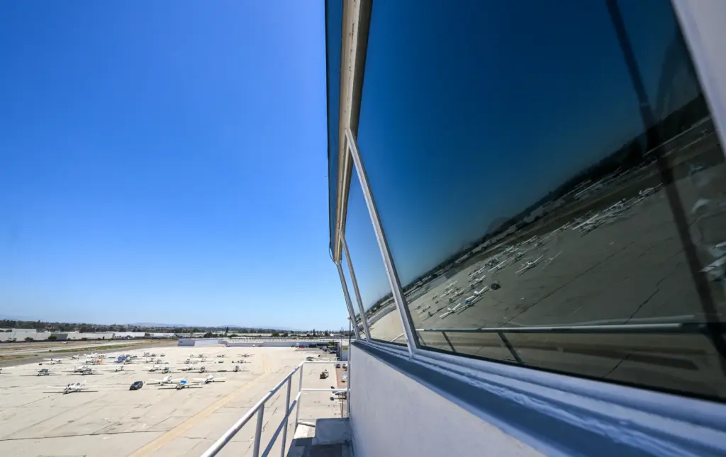Parked aircraft are reflected in the window of the control...