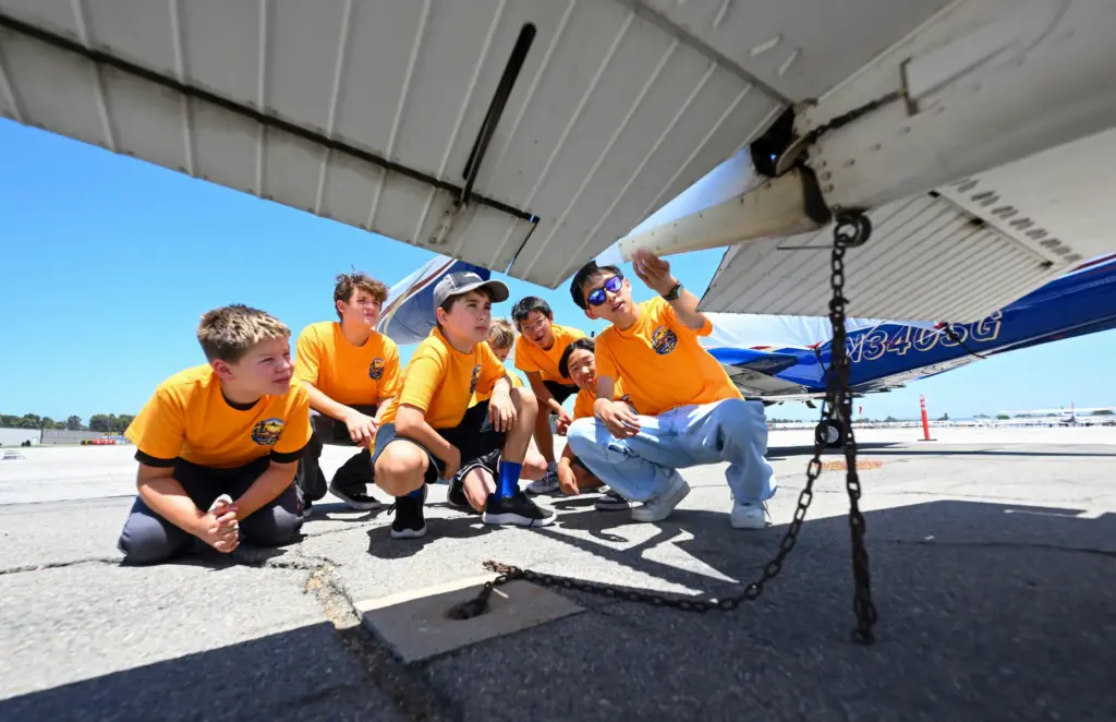 Counselor Baominh Dang shows campers how to preflight an Cessna...