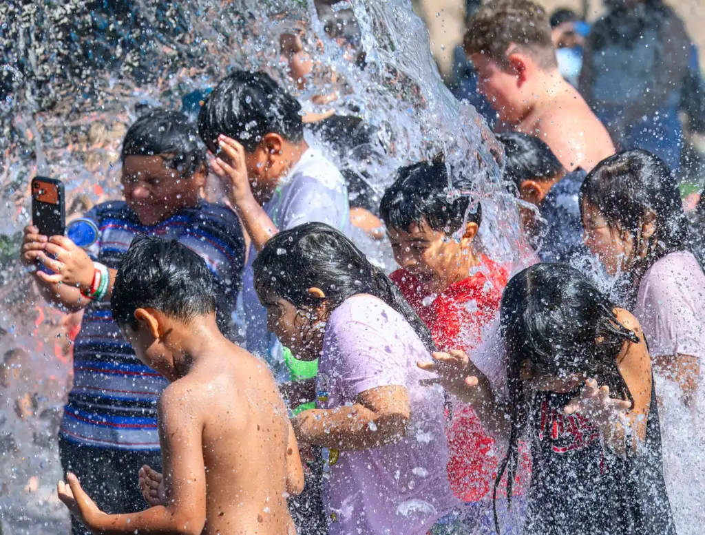 Kids cool off as a bucket of water splashes on...
