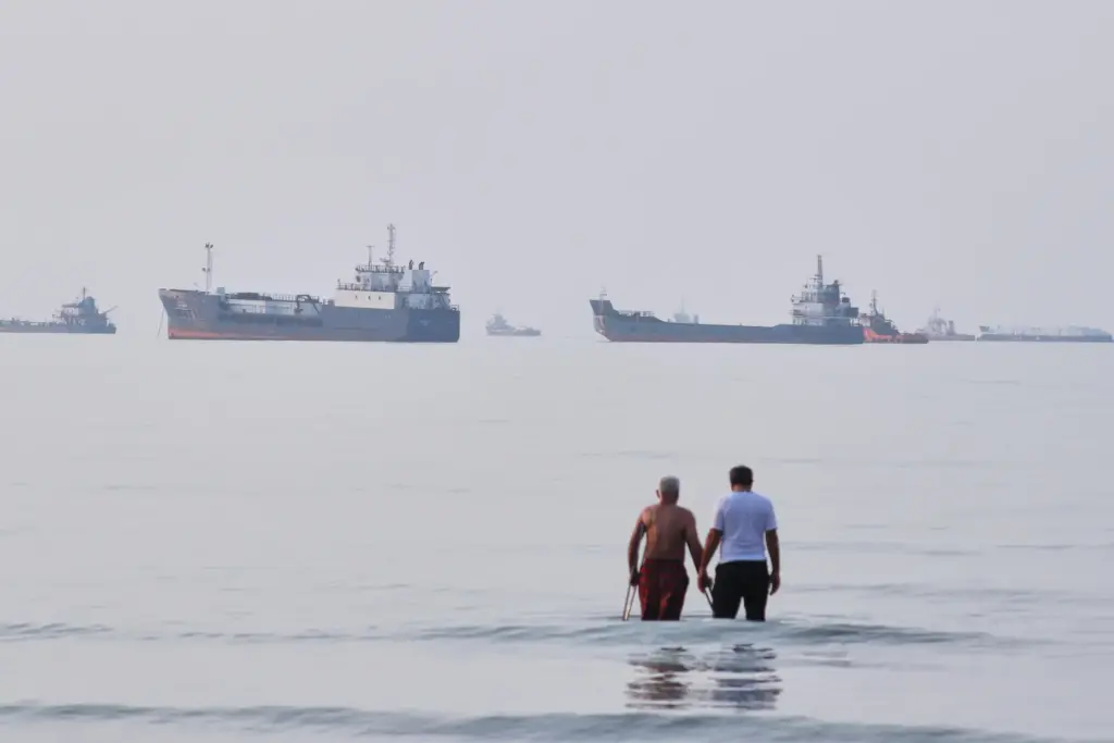 Two men wade in the waters of the Strait of...