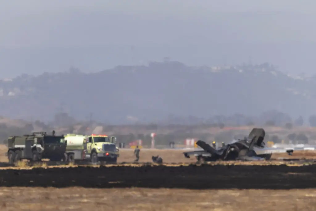 Crews work to douse a F-35 fighter jet that crashed...