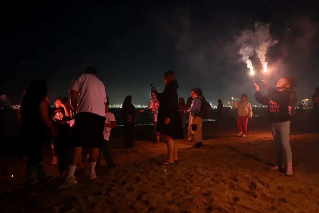 Children play with sparklers as simultaneous fireworks displays in Long...