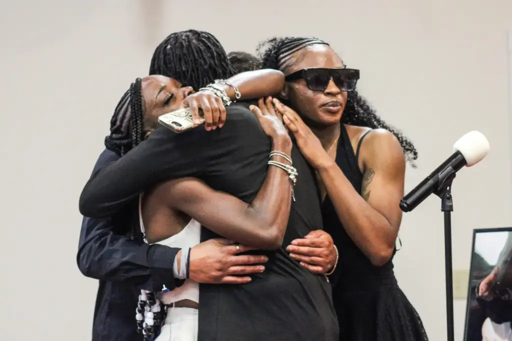Some of Lloyd Gilmore's children embrace during his funeral.