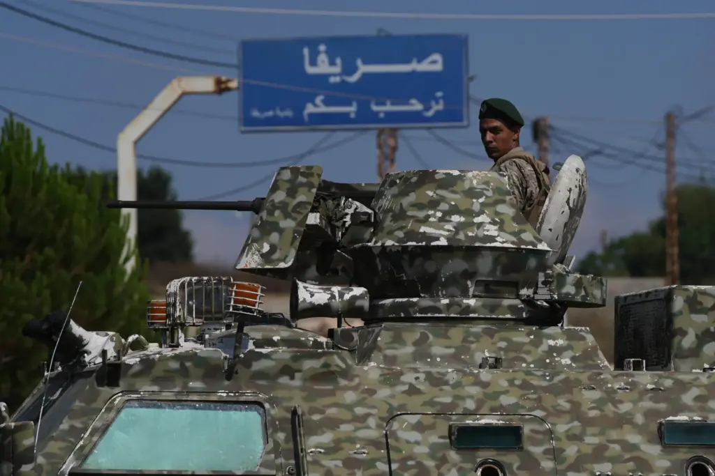 A Lebanese soldier stands atop an armored personnel carrier while...