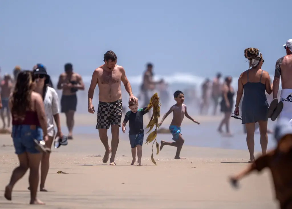 Beachgoers hang out on the sand and in the water...