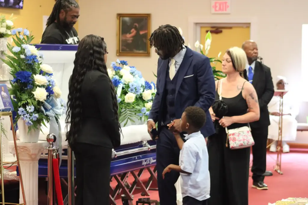 Andre Young and his 5- year-old son view Lloyd Gilmore's body during his funeral.
