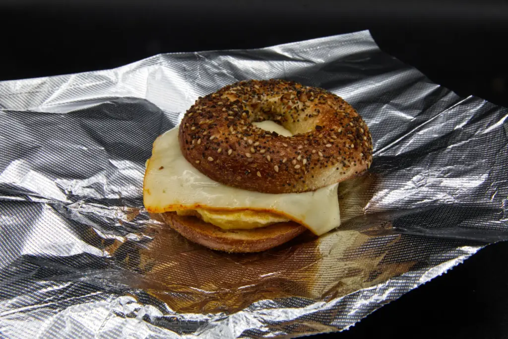 A breakfast egg and cheese on an “everything” bagel photographed...