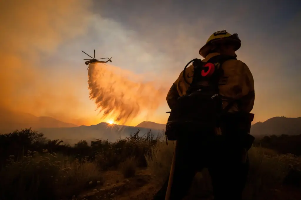 A firefighter watches as a helicopter drops water on the Summit Fire.