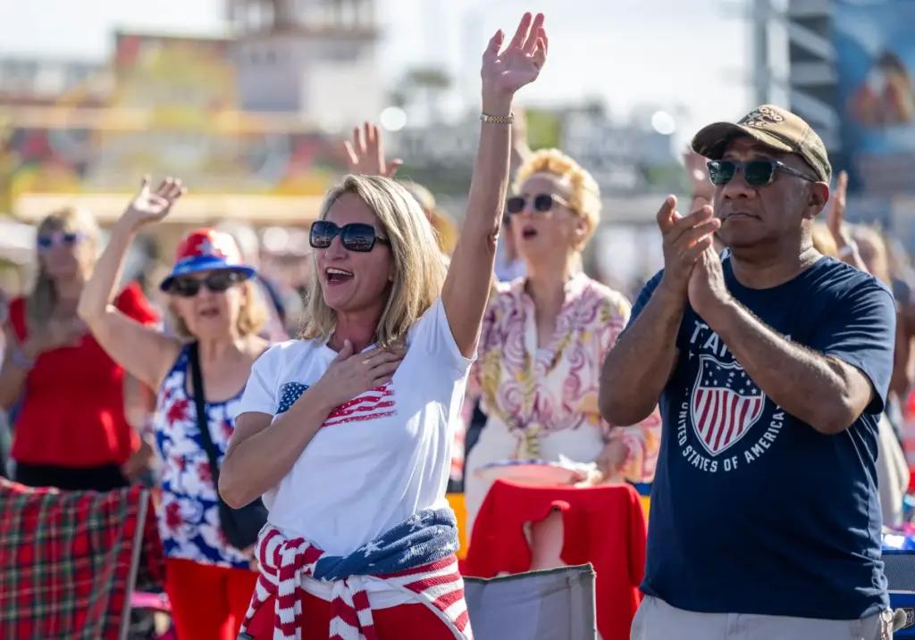 Audience members sing along to the national anthem during the...