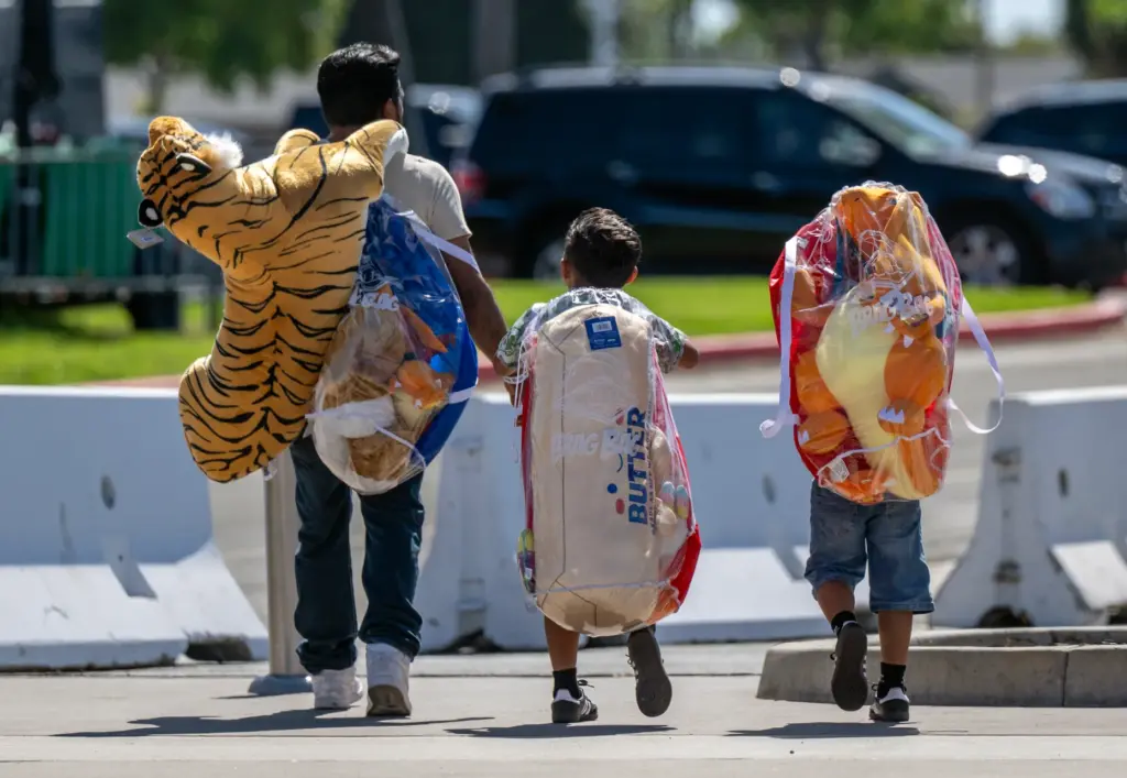 Fairgoers carry several stuffed game winnings as they walk to...