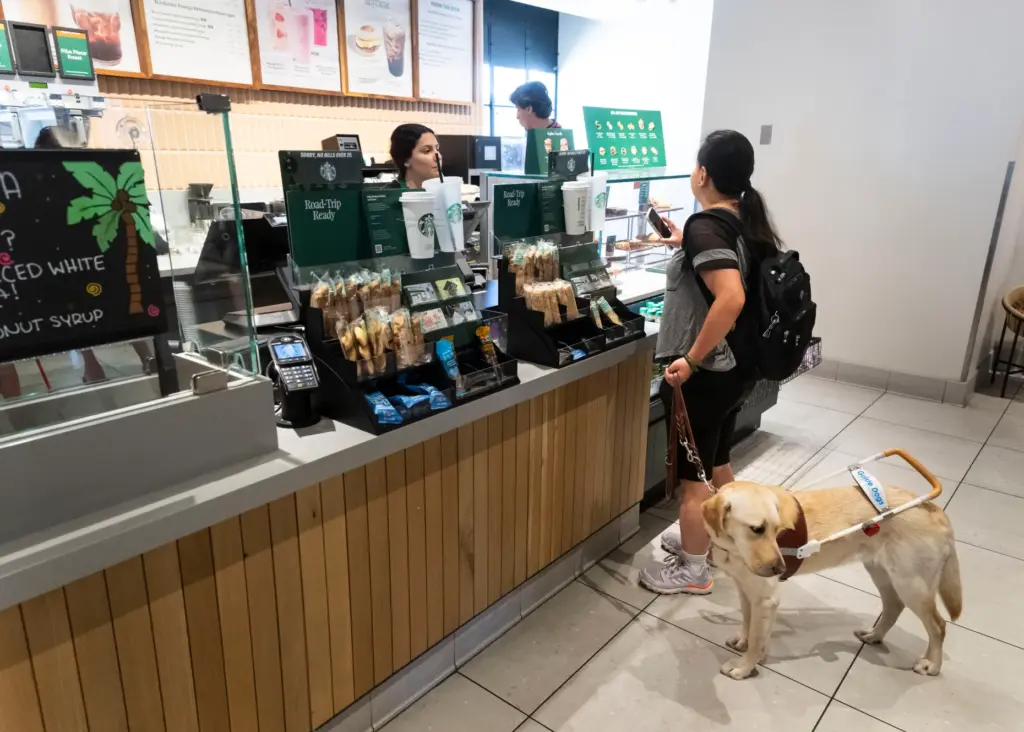 Camp volunteer Tiffany Zhao, with her guide dog, orders at...