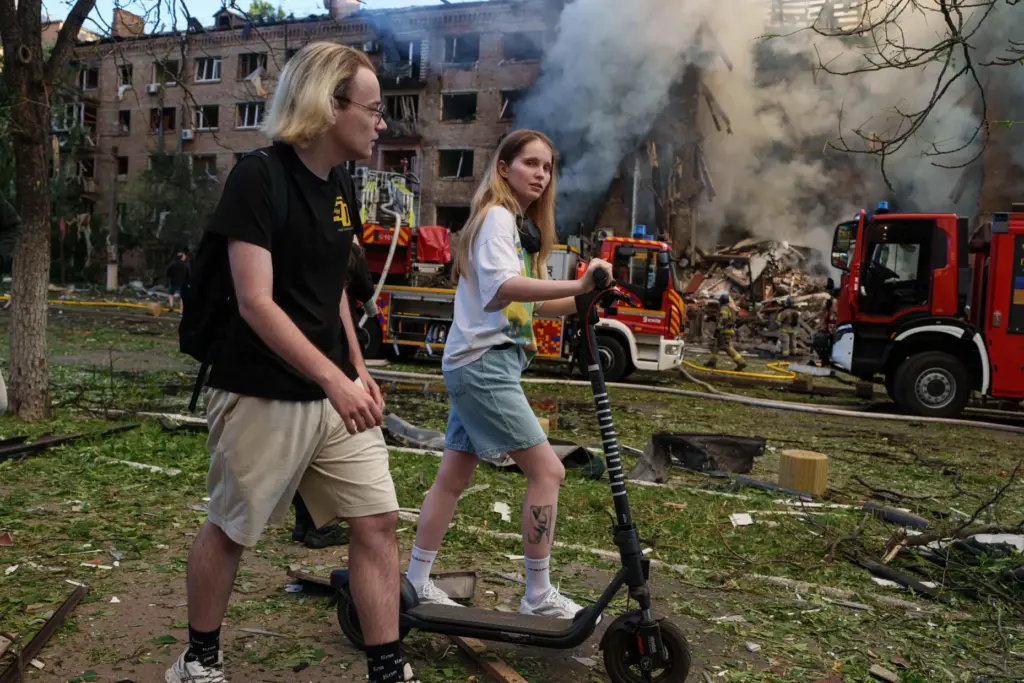 People walk past a smoldering residential building destroyed by a...