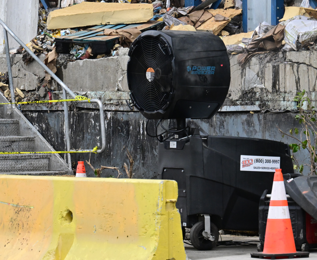 A large fan blows outside the burned warehouse. Residents and...