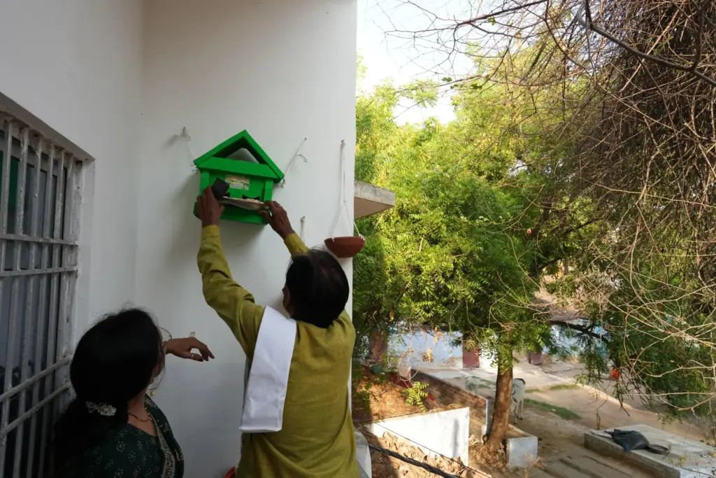 Bird conservationist Shobharam Kashyap installs a wooden birdhouse for sparrows...