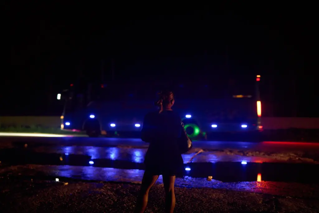 A transgender sex worker stands next to a busy highway...