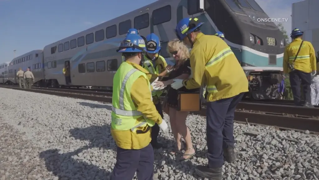 Anaheim and Placentia firefighters assist passengers off a Metrolink train...