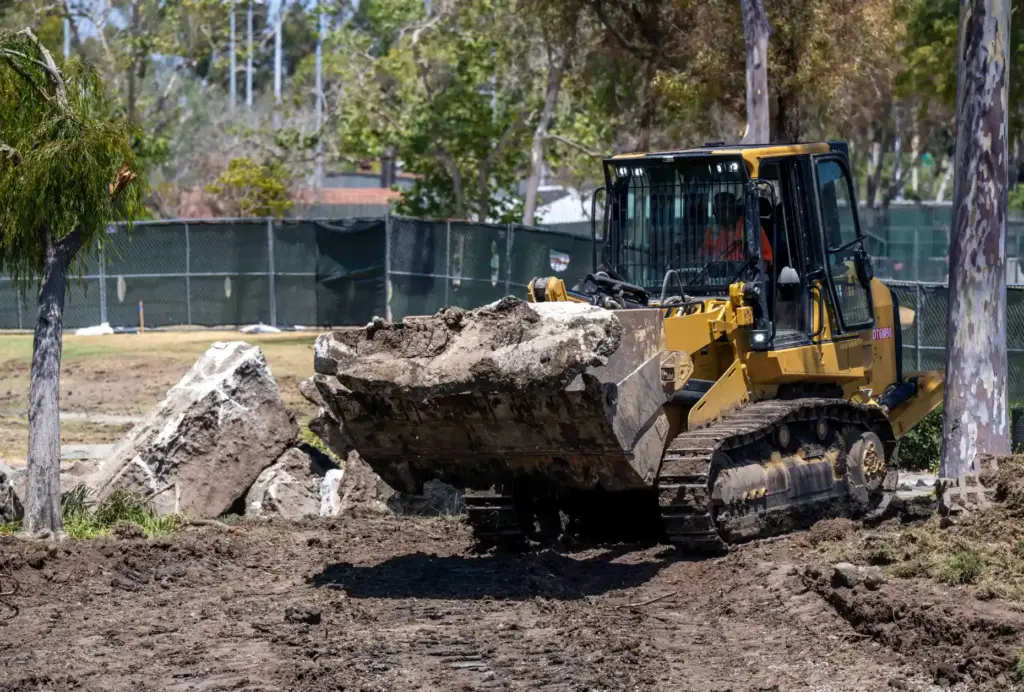 Workers use heavy equipment to grade the lower lakebed as...