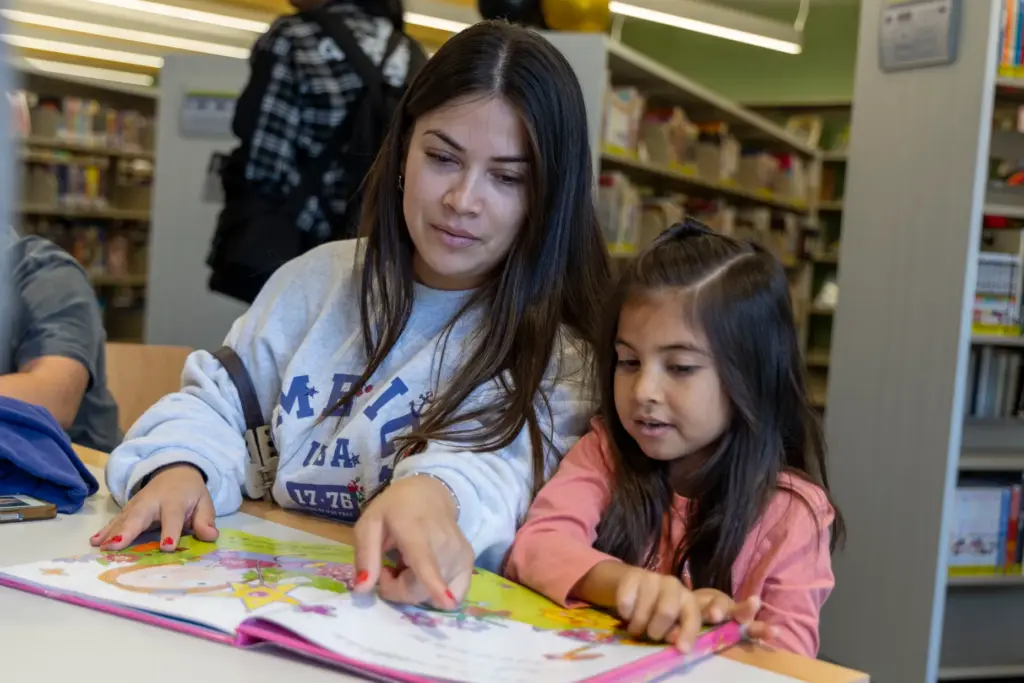 Genesis Martinez (left) reads a book with her sister, Mikayla...