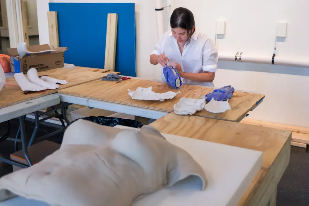 Artist Misty Choi separates a mold from a plaster body...