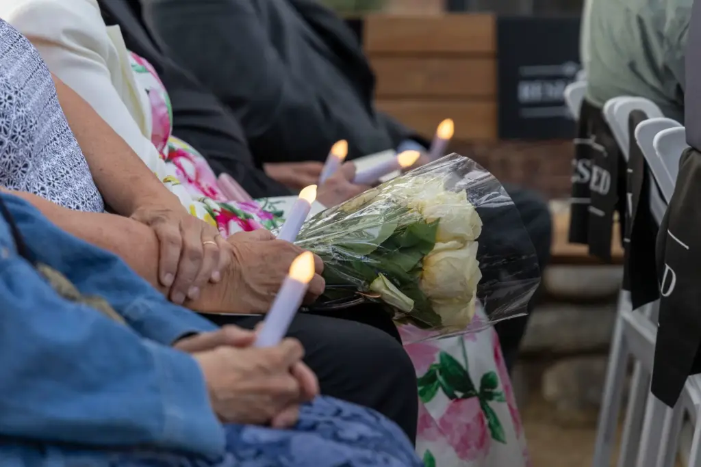 Attendees of a 50th anniversary candlelight vigil hold lit candlesticks...