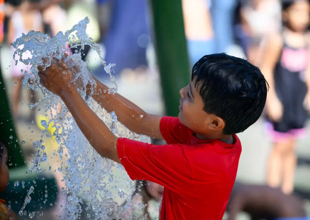 A boy plays with the water spouting from the new...