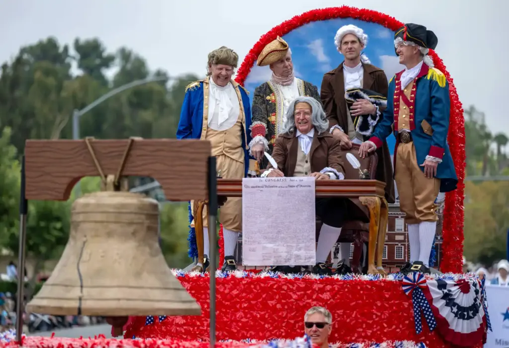 The Founding Fathers, huddled around the Declaration of Independence, ride...