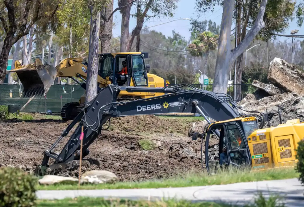 Workers use heavy equipment to grade the lower lakebed as...