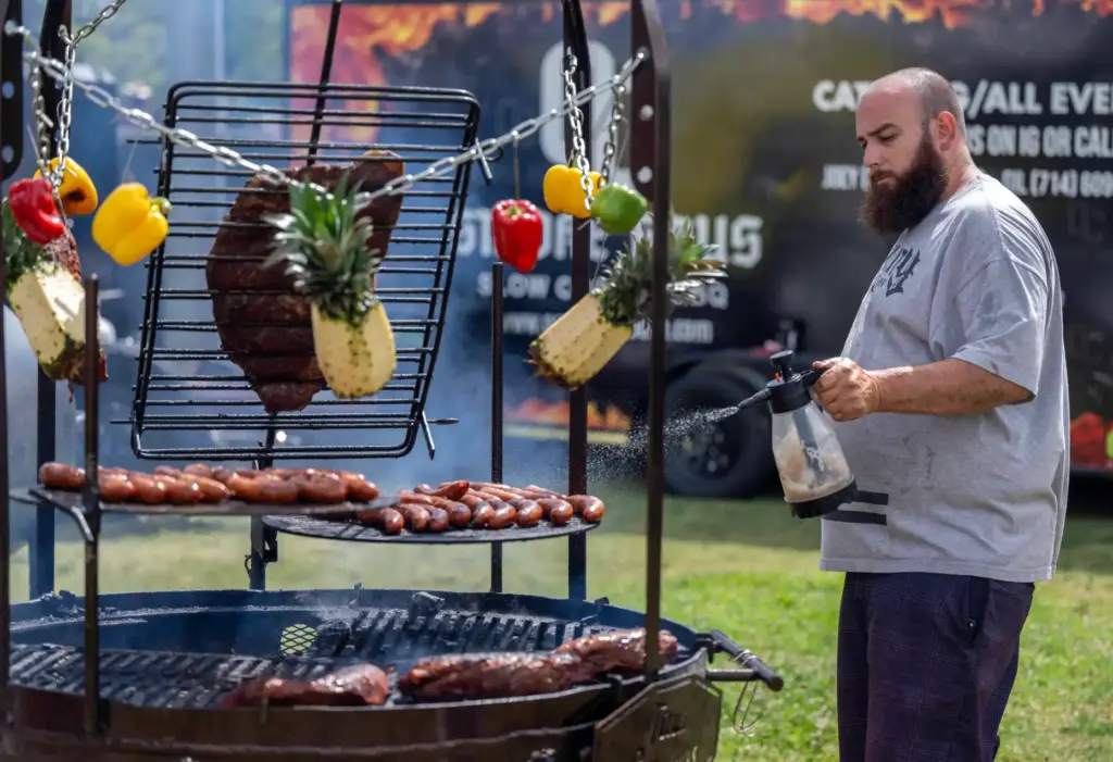 Joseph Prange, co-owner of OC Smoke Haus, sprays apple juice...