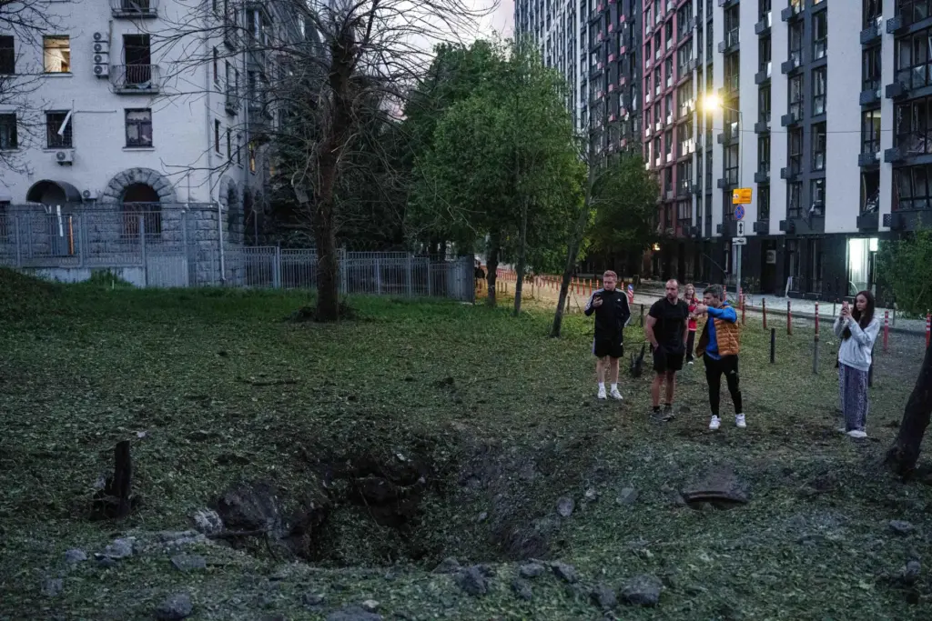 FILE – People stand by a crater from a Russian...