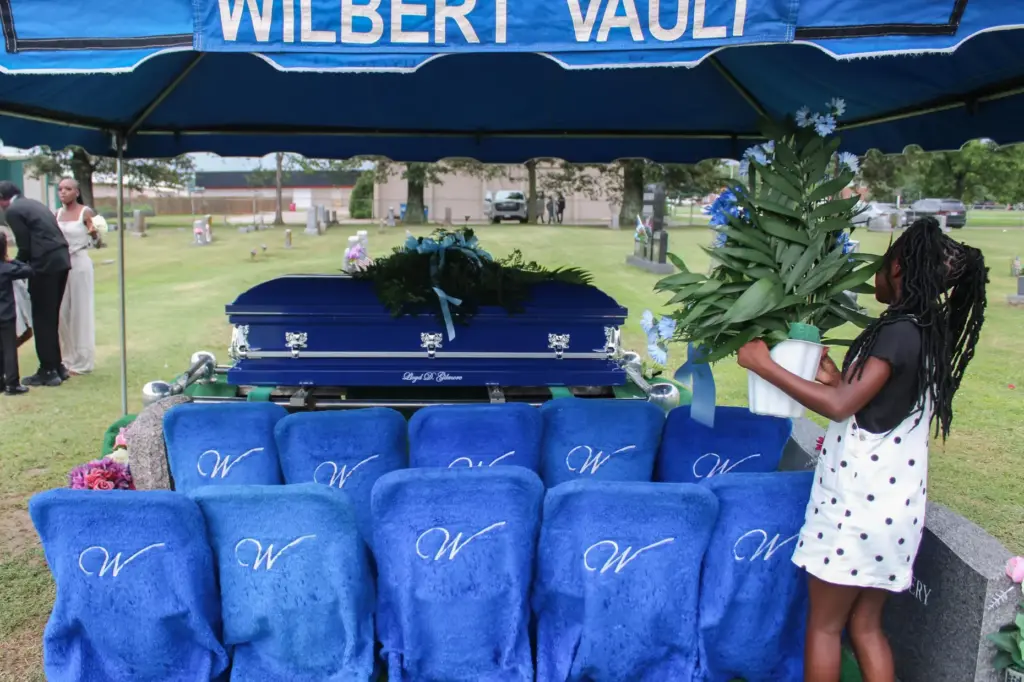 One of Lloyd Gilmore's granddaughters picks up a flower arrangement at a cemetery.