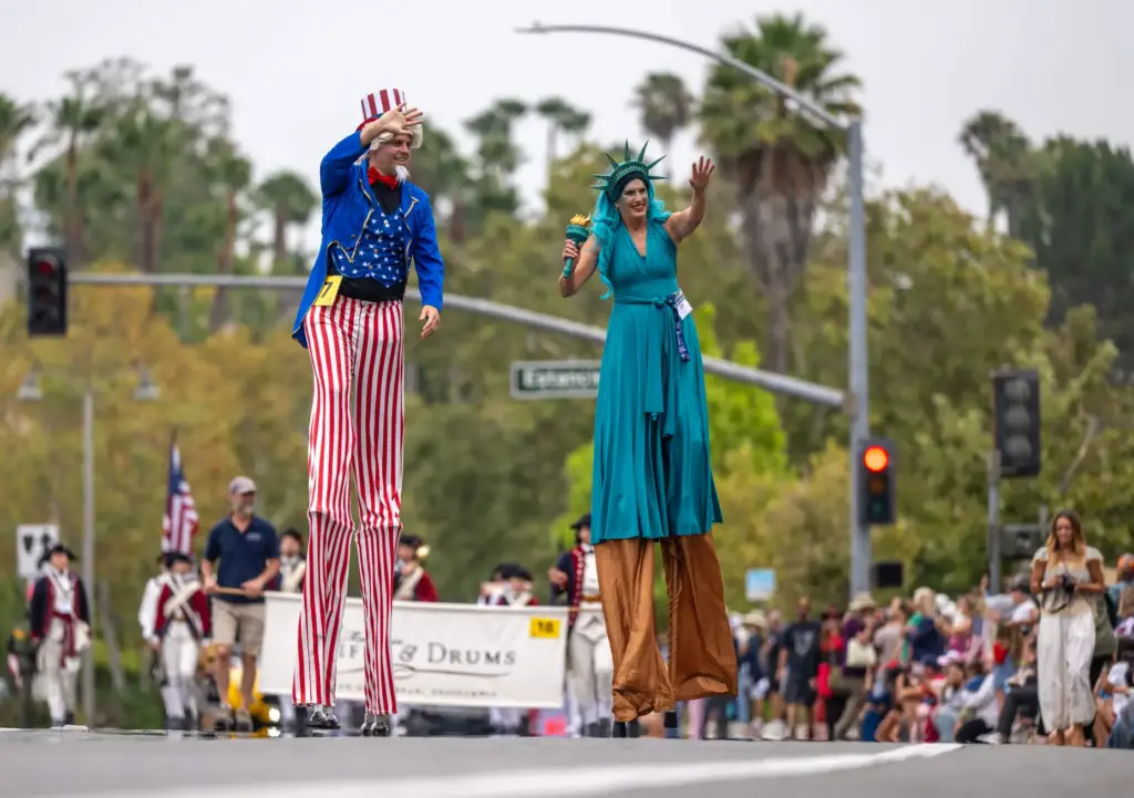 Stilt performers dressed as Uncle Sam and Lady Liberty walk...