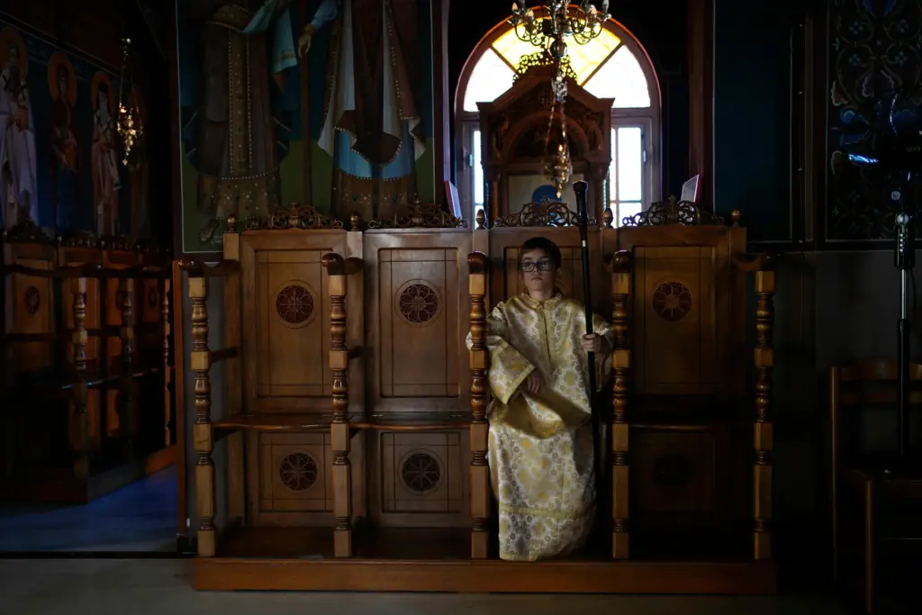 Pantelis, an altar server, sits at the Church of St. Fanourios.