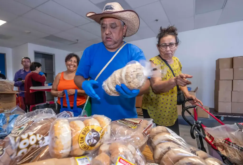 Volunteer Ricardo Castelaso helps distribute food to community members at...