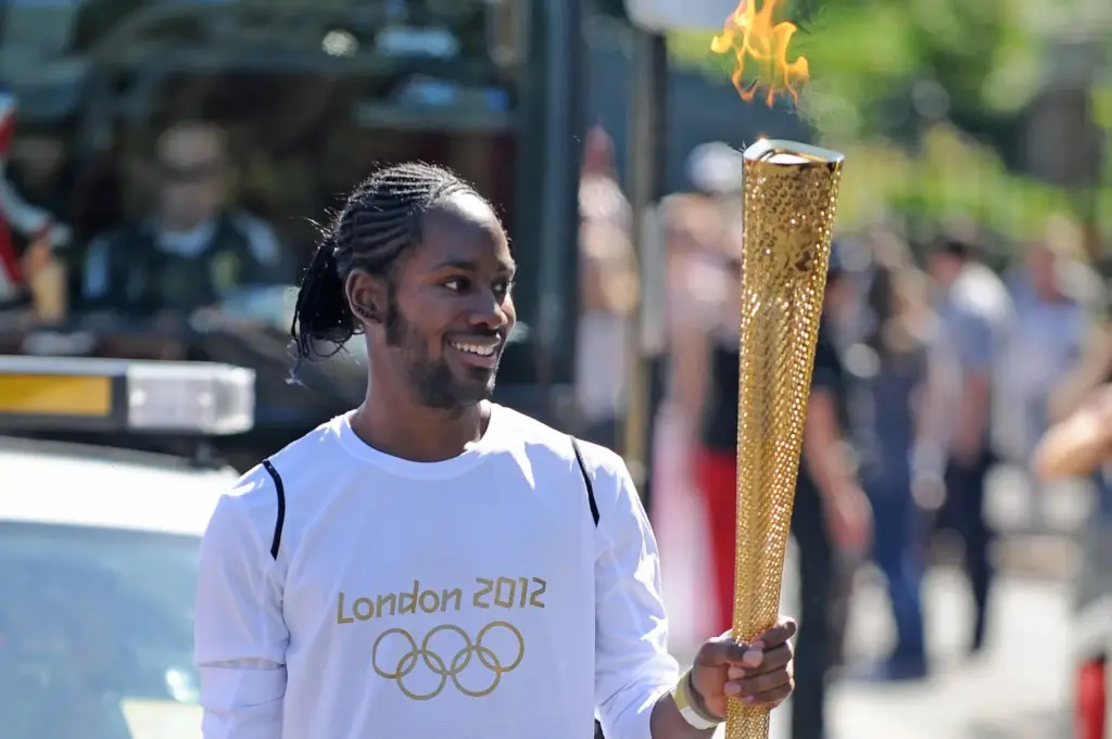 Torchbearer Jason Arday carries the Olympic Flame on the Torch...