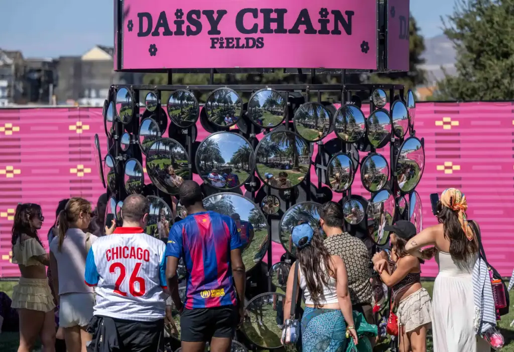 Festivalgoers pose in front of a mirror installation at the...