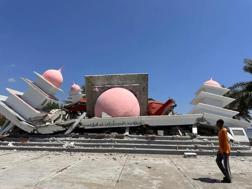 A man walks past a mosque collapsed during an earthquake in Lamba Leda, Indonesia.