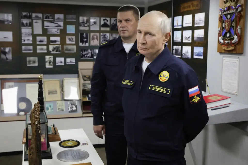 Russian President Vladimir Putin and Admiral Viktor Liina listen to a navy officer.