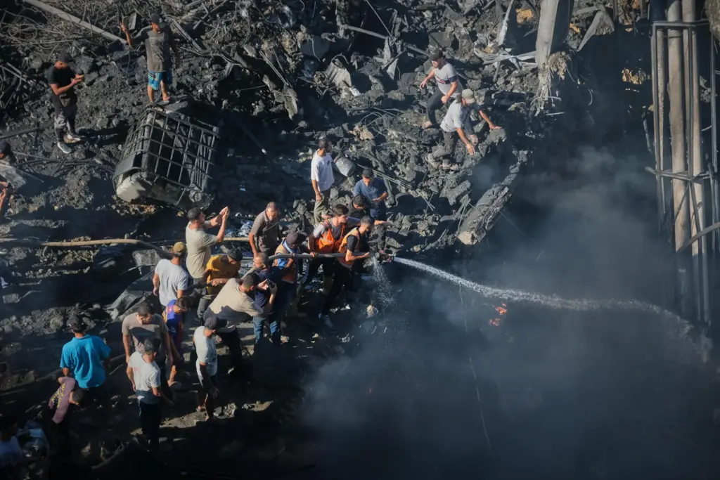 Palestinians try to extinguish a fire in the rubble of...