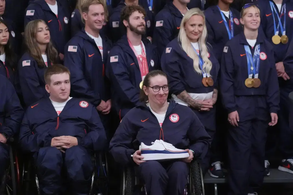 President Donald Trump speaks as alpine monoskier Laurie Stephens smiles.