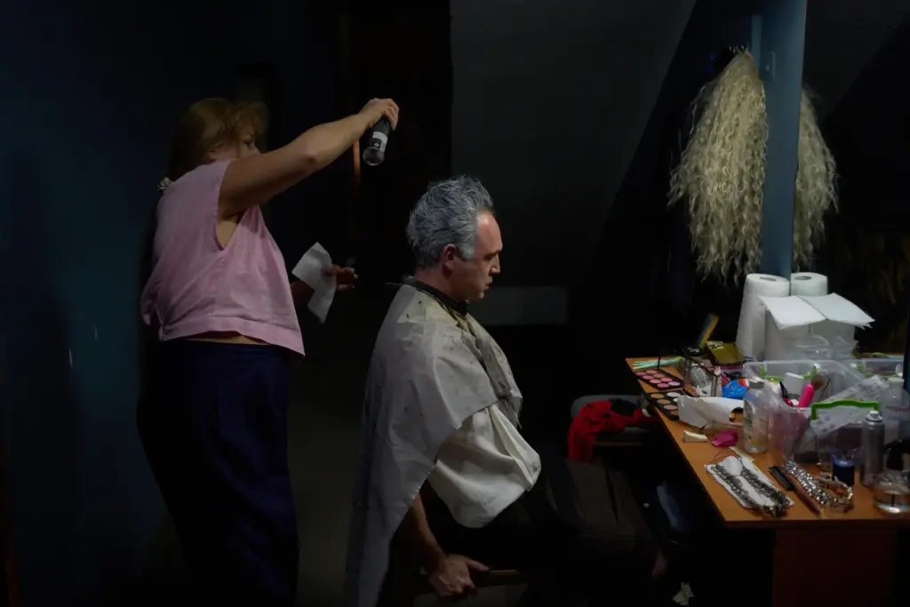 An actor gets his hair styled backstage before the final rehearsal of 